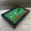 Miniature pool table with colorful balls and cues on a gray surface.